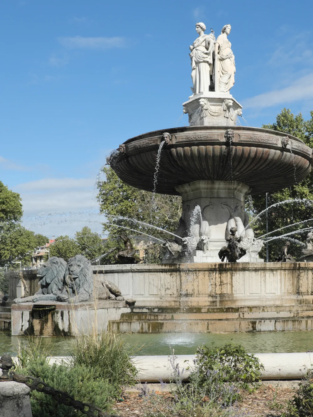 The Fontaine de la Rotonde in Aix-en-Provence, with its statues and lions, under a blue sky