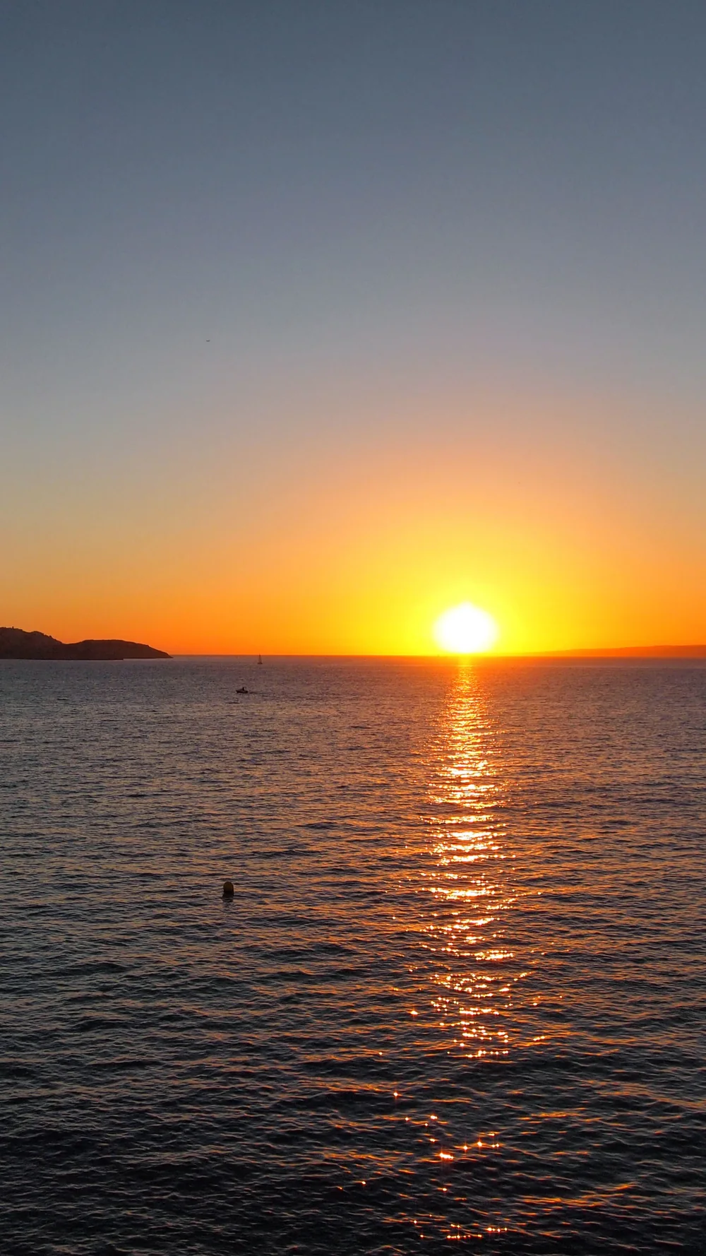 The sun setting over the sea in Marseille, casting a golden trail on the water