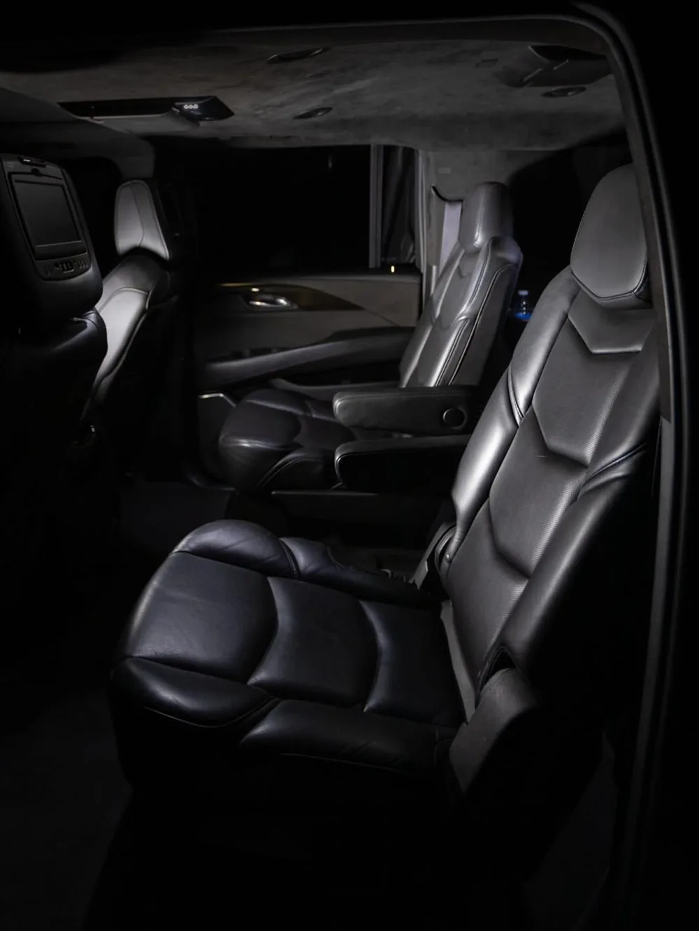 Dark leather rear seats of a luxury SUV, in low light