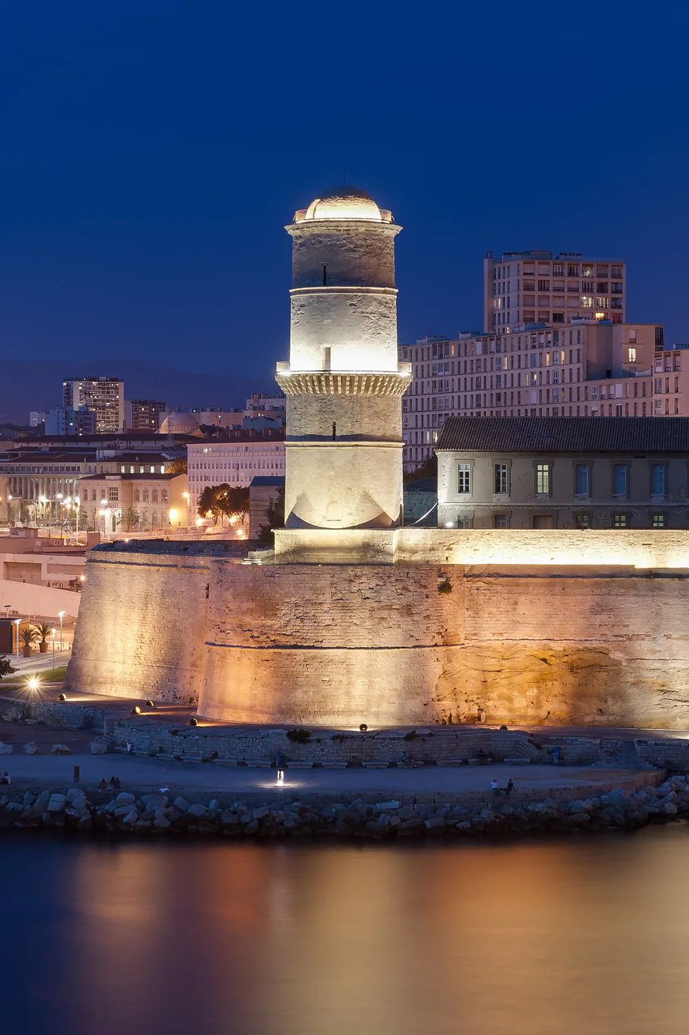 An illuminated tower and ramparts on the Old Port of Marseille at blue hour